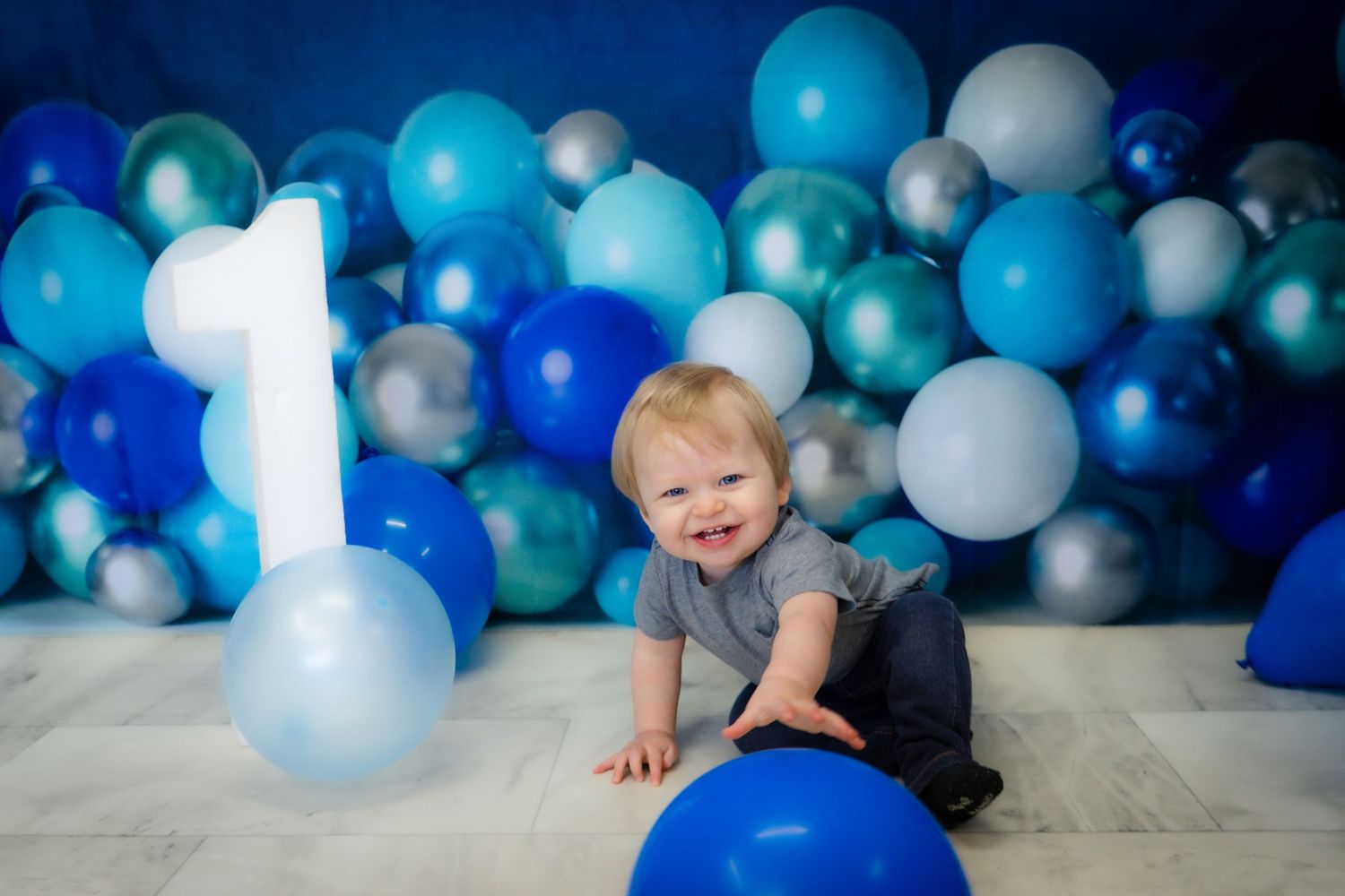 First birthday photo shoot with blue and white balloon arch background.