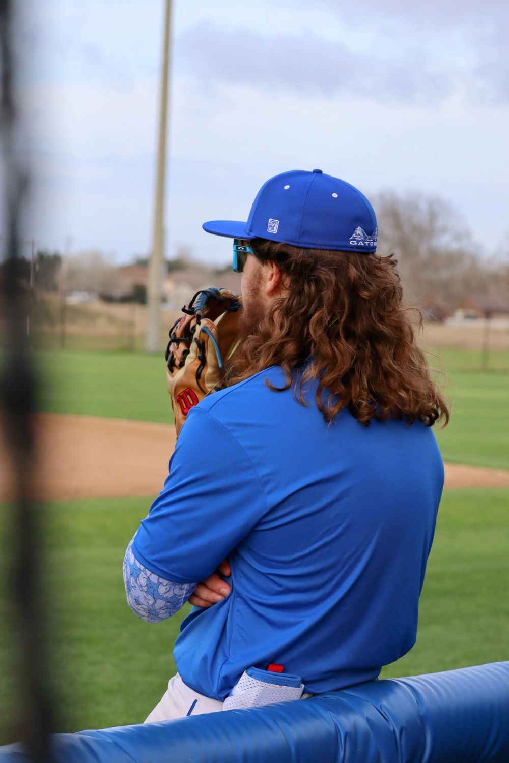 Baseball photographer in blue capturing game action from sideline position.