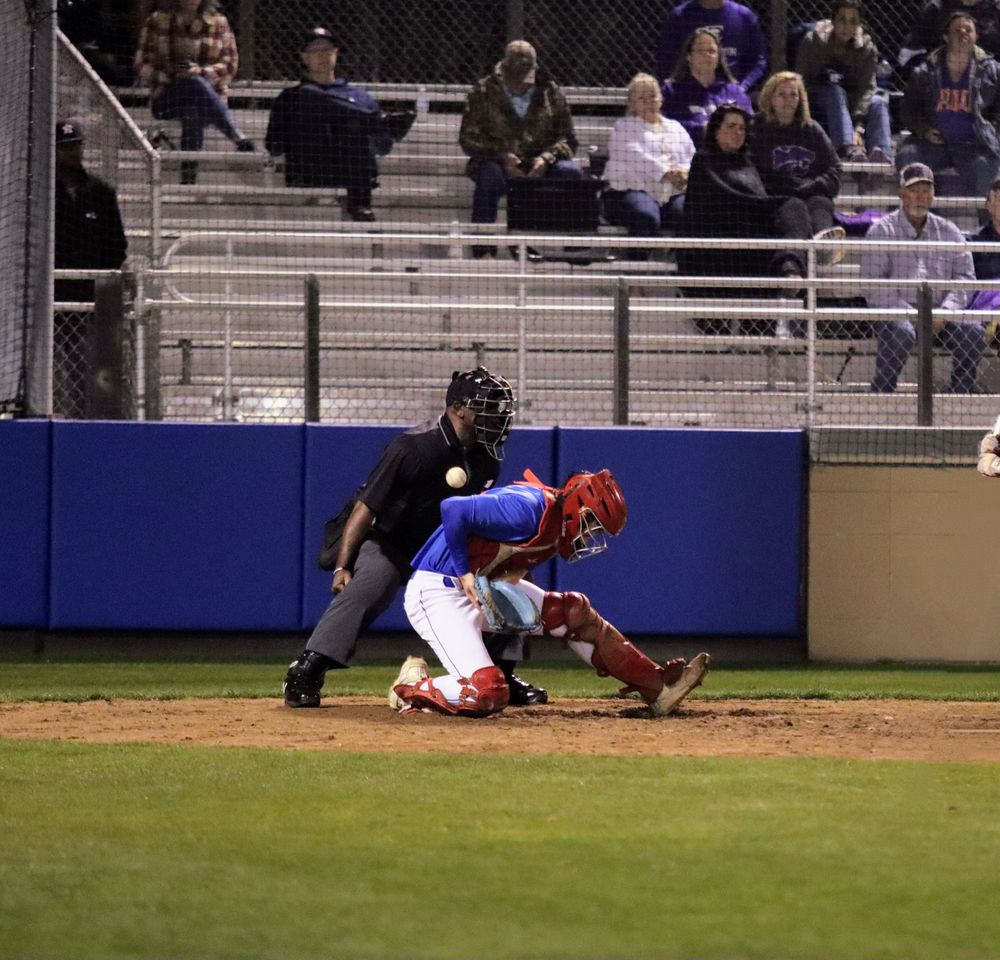 Baseball action at home plate with catcher and umpire during a competitive game.