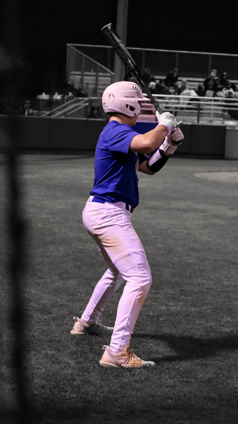 Baseball player in blue uniform demonstrating batting stance on field.