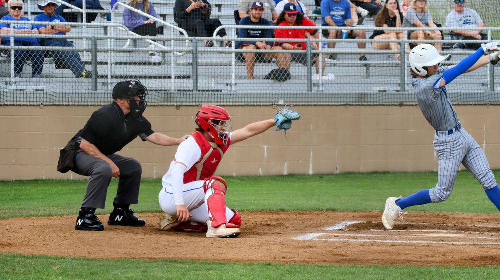 Baseball game action at home plate with batter, catcher and umpire.