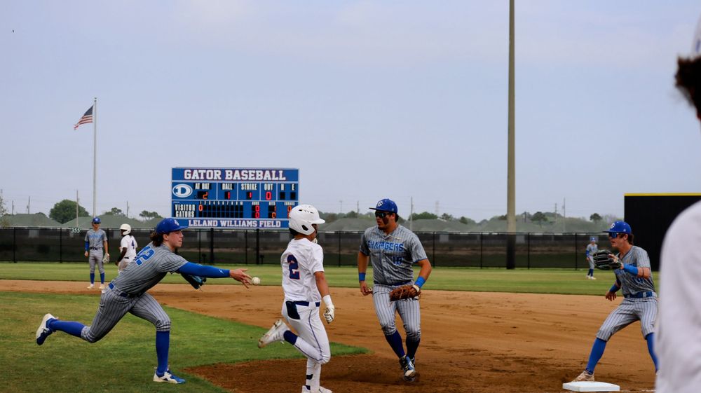 Baseball game action with players running between bases under stadium lights.