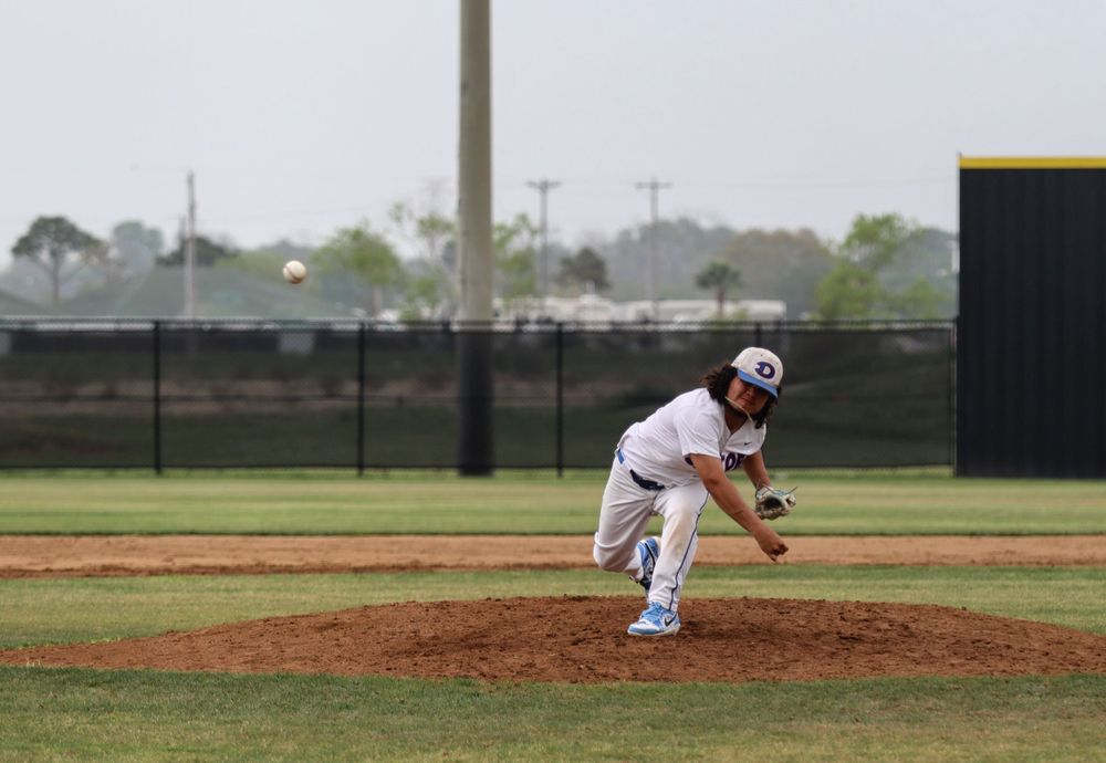 Baseball pitcher in mid-delivery motion on dirt mound during game.