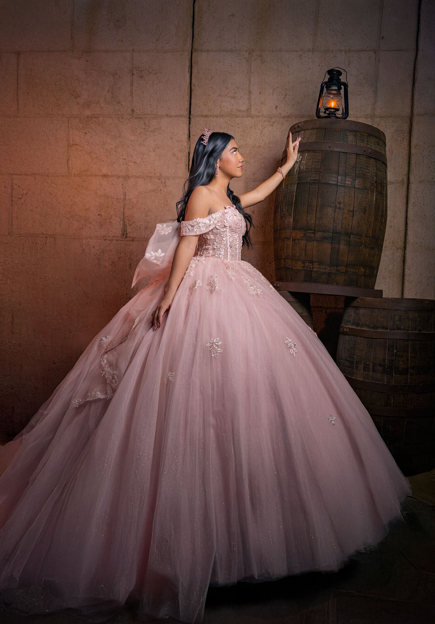 A stunning pink ballgown with tulle skirt and floral appliques photographed in sequence against rustic wooden barrels.