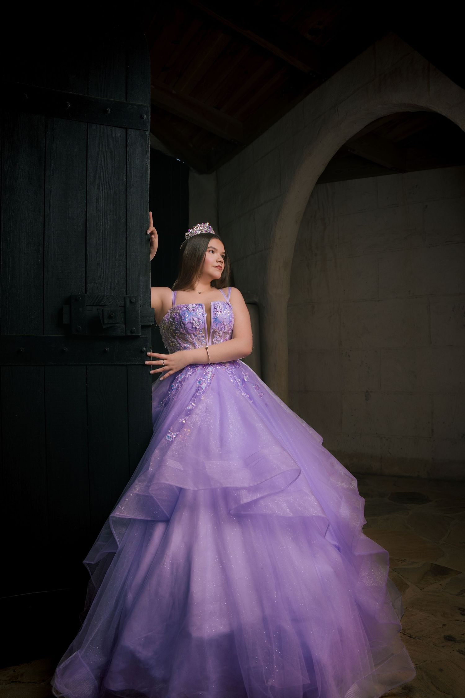 Ethereal portrait in a flowing purple ball gown against dark castle interior.