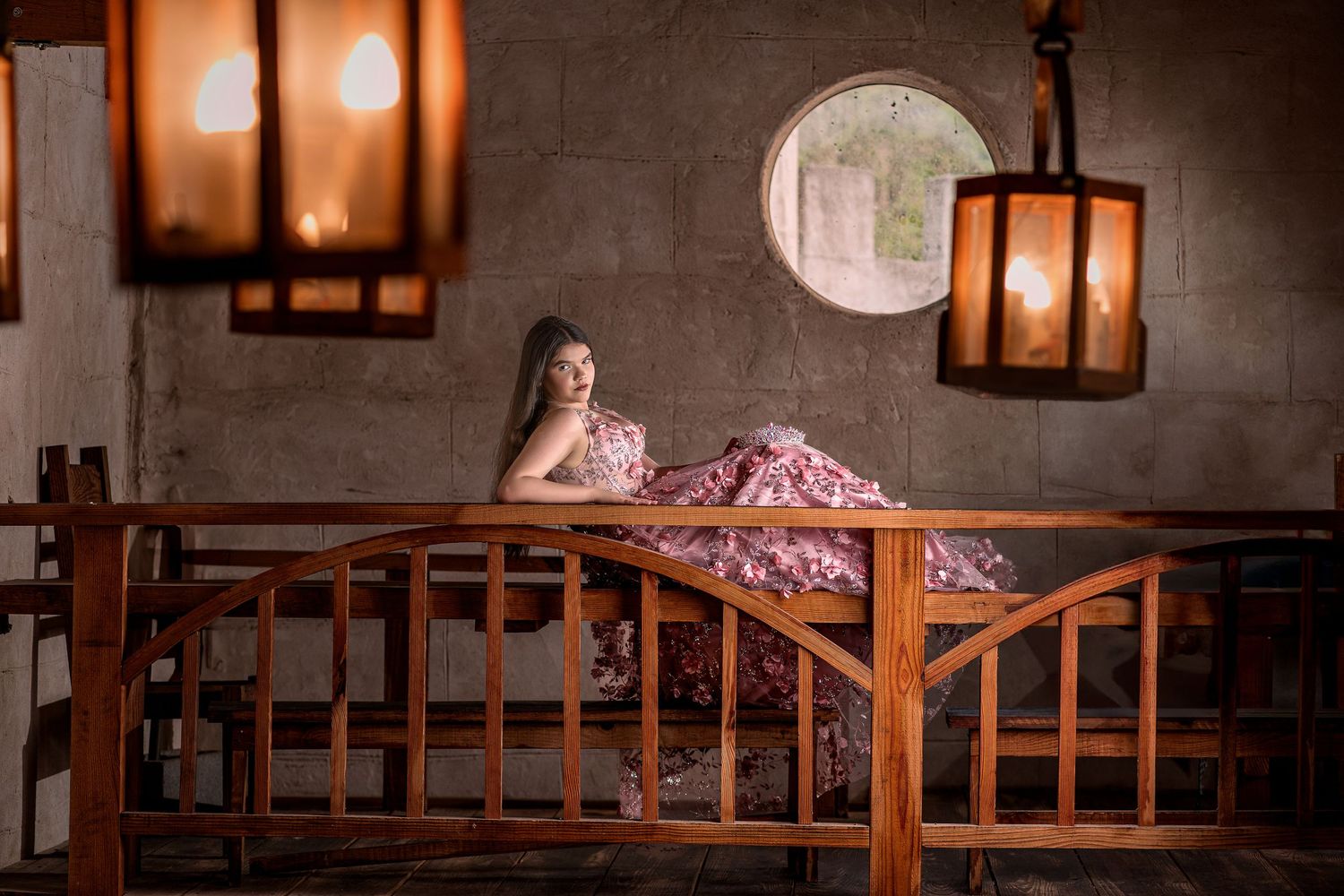 A lavish quinceañera dress shimmers in warm lighting against wooden railings and vintage lanterns.