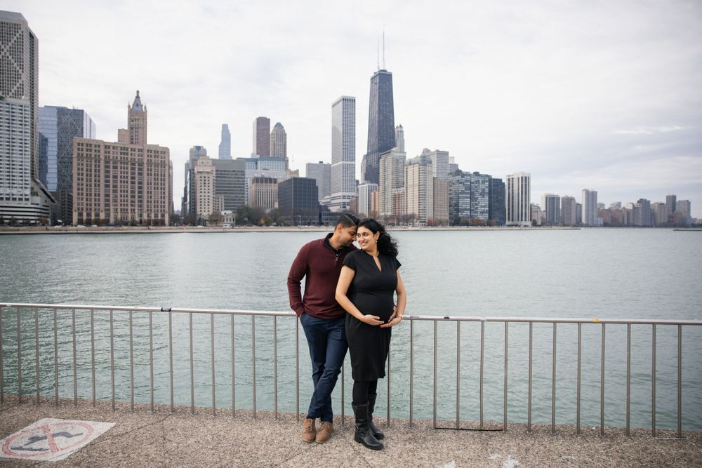 A couple shares an intimate moment along Chicago's waterfront with the skyline behind them.