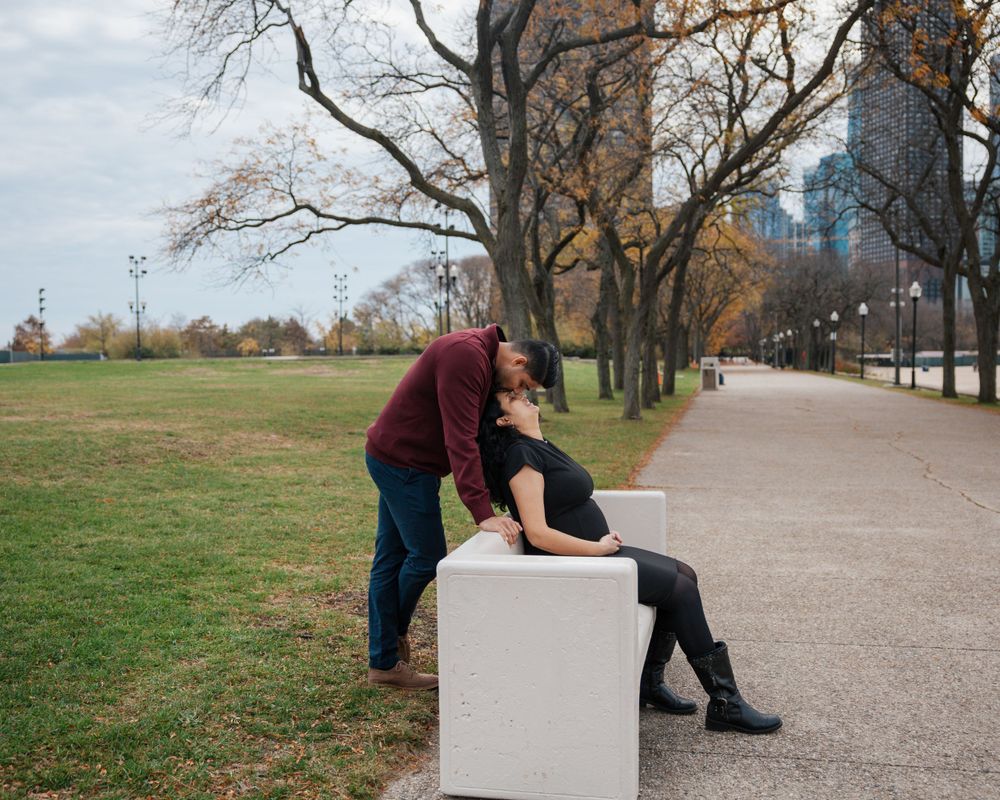 Two people share a tender moment on a concrete block along Chicago's lakefront path.