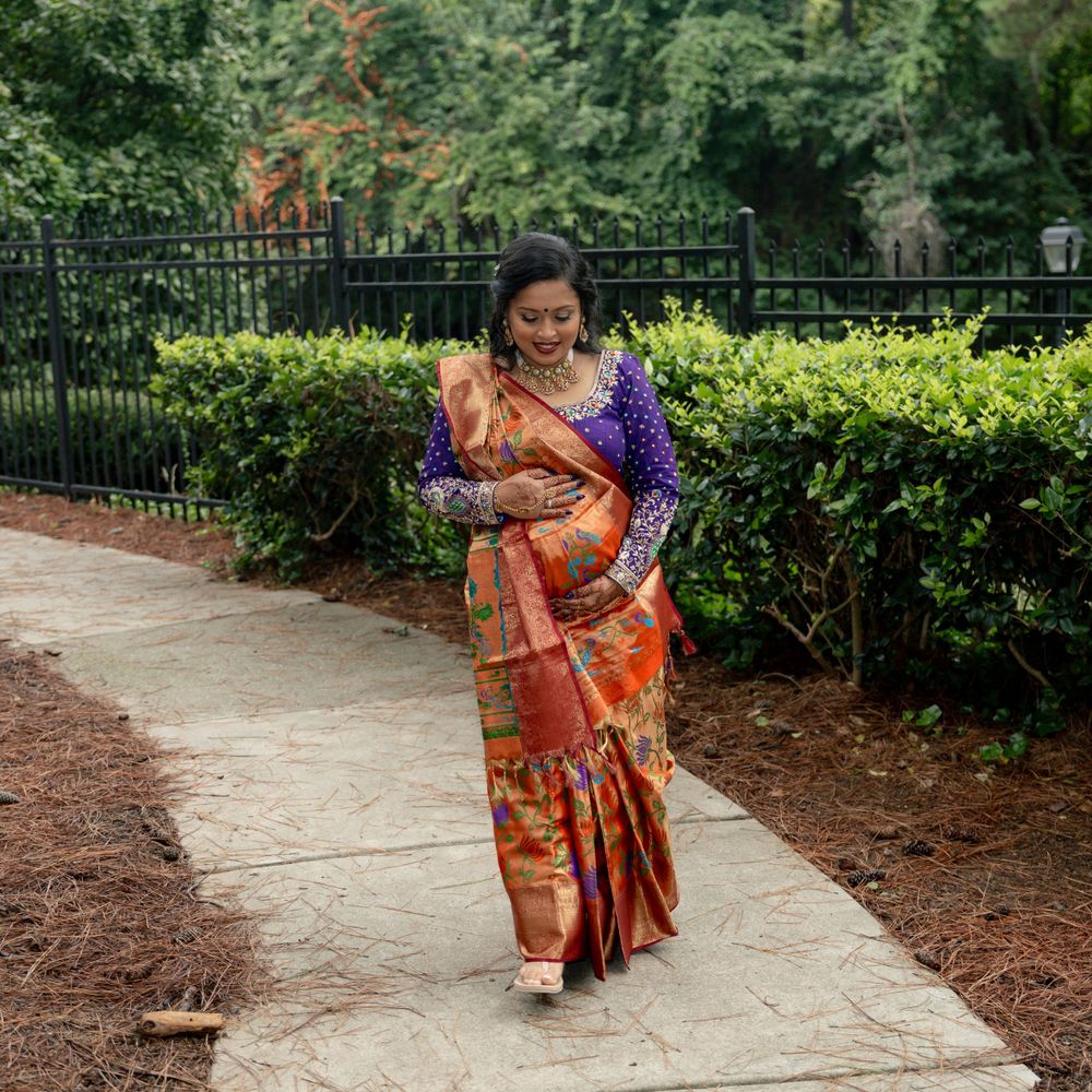 A person in a vibrant orange and purple sari walks along a garden pathway.