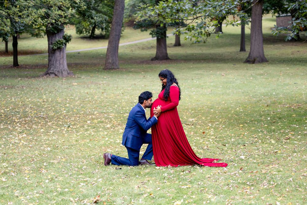 A romantic moment unfolds in a park as one person kneels before another wearing a flowing red dress.