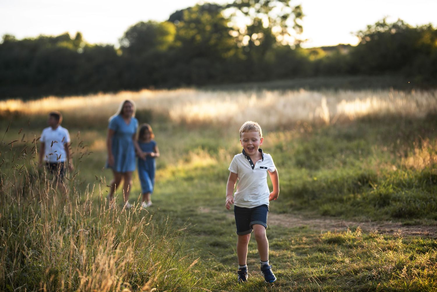 Family enjoying golden hour sunset in a grassy meadow during outdoor photoshoot.
