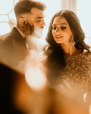 Intimate moment captured in warm sunlit setting with elegant formal attire.