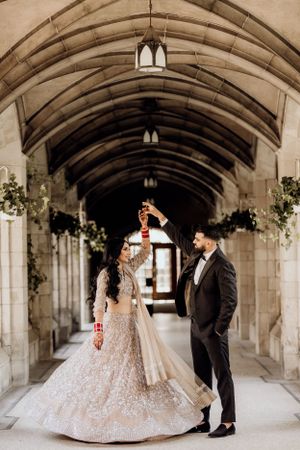 Elegant wedding portrait in stone corridor with vaulted ceiling and hanging lanterns.