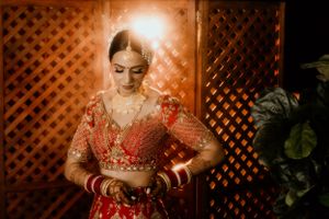 Traditional Indian bridal outfit captured through wooden lattice with dramatic lighting.