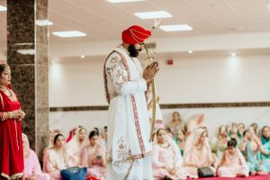 Traditional Sikh wedding ceremony with guests seated on floor in indoor venue.