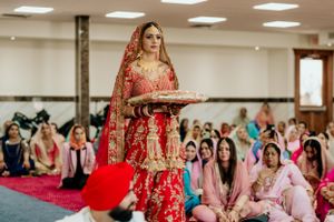 Traditional Indian wedding ceremony with guests watching bride in red lehenga.
