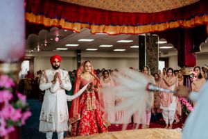 Sikh wedding celebration with traditional outfits and decorative indoor setting.