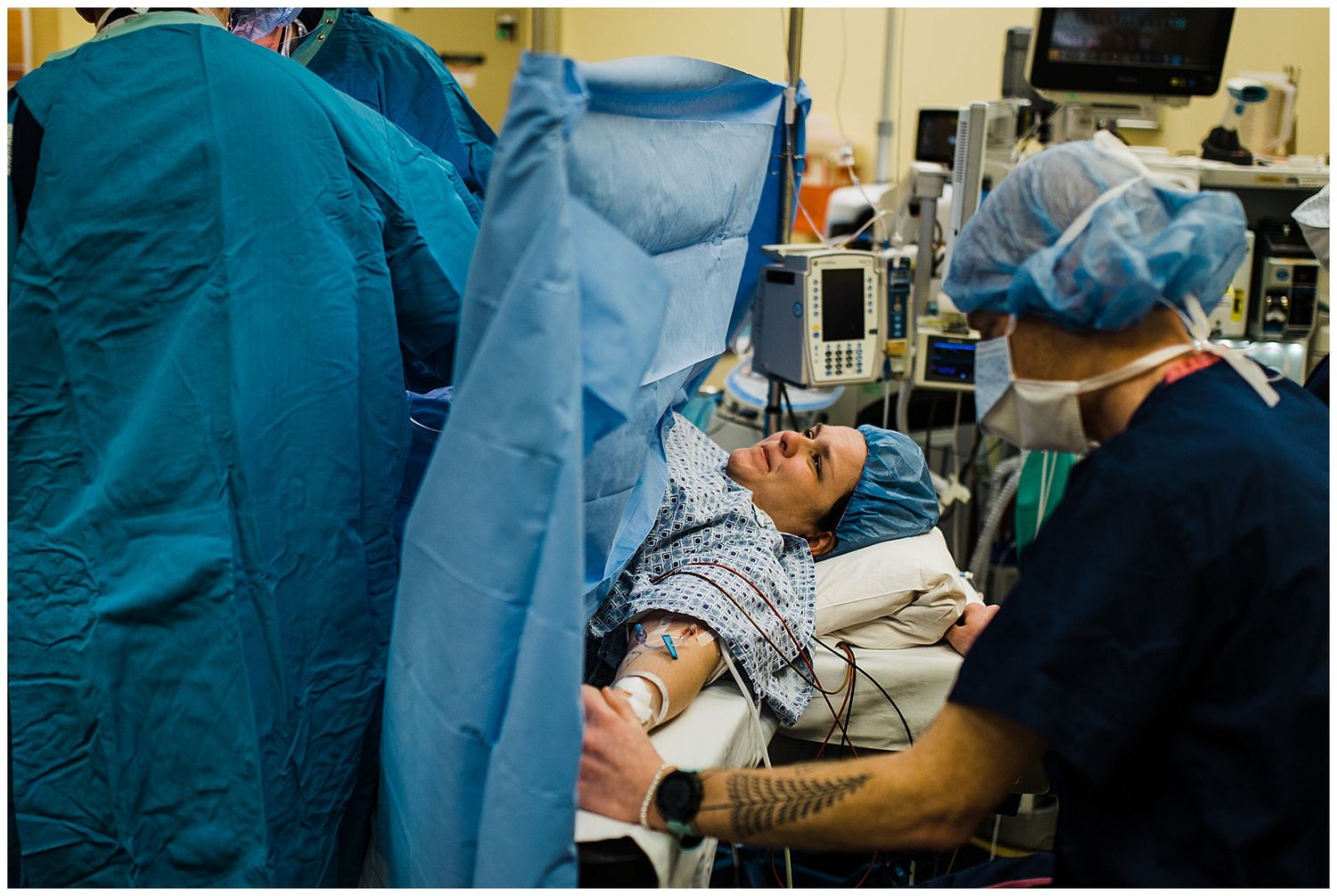 Medical staff in surgical gowns and masks attend to a patient in an operating room.