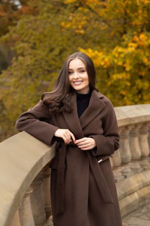 Autumn fashion portrait featuring brown wool coat against golden foliage background.