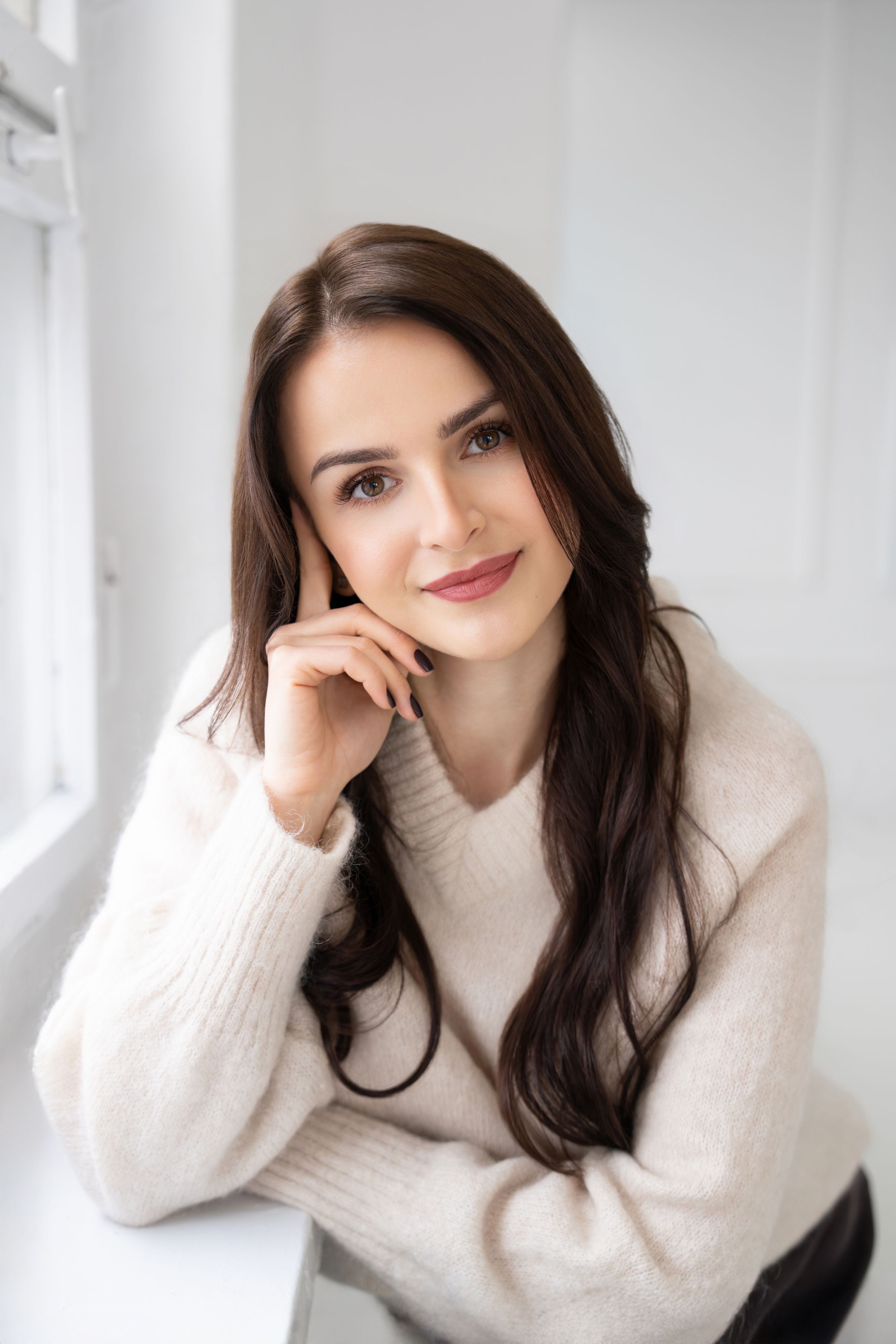 A person in a cozy white sweater poses against a bright white background in a series of casual portraits.