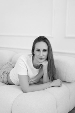 Casual portrait on cream couch in minimalist white room setting.