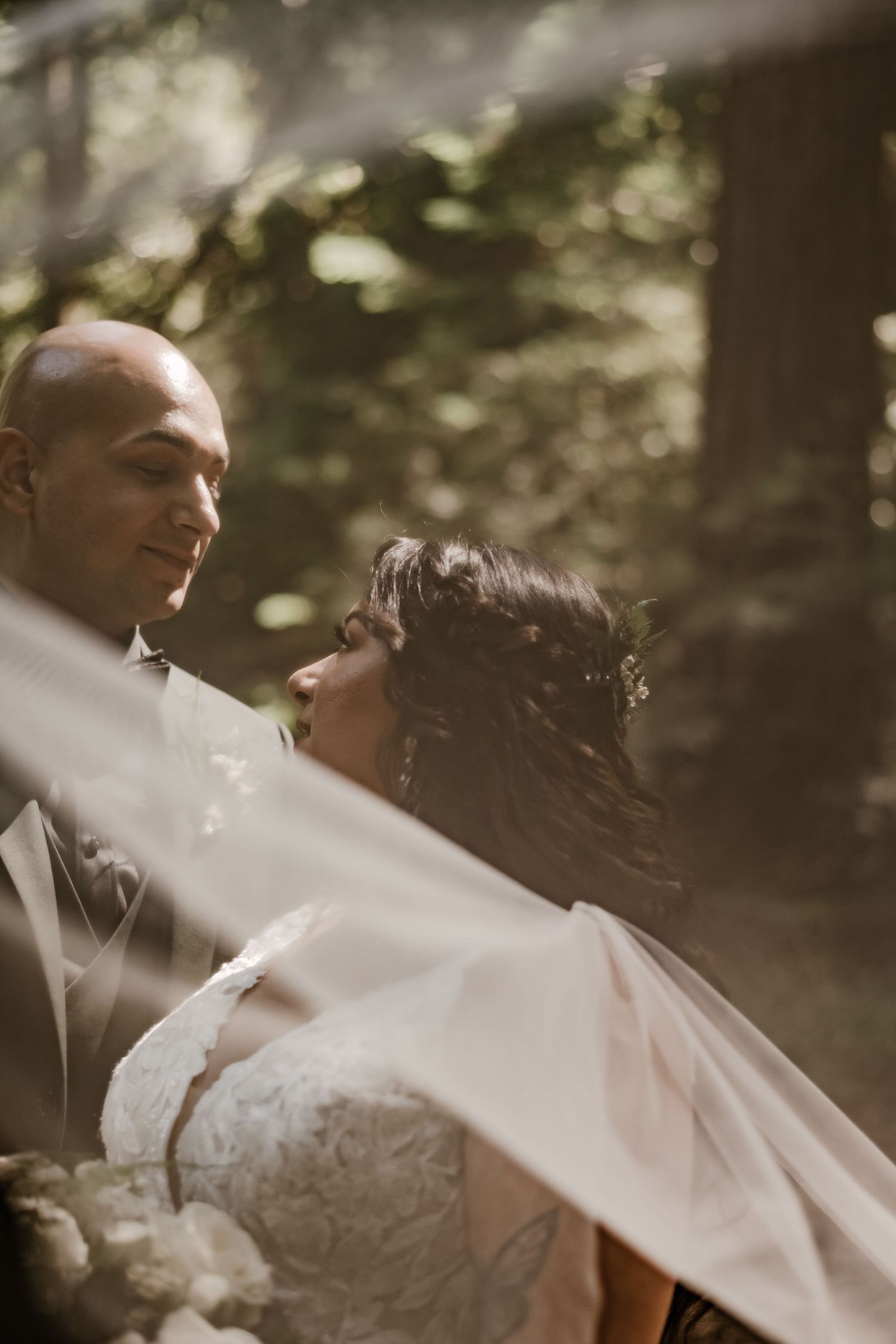 Romantic wedding moment captured through a delicate veil in soft natural lighting.