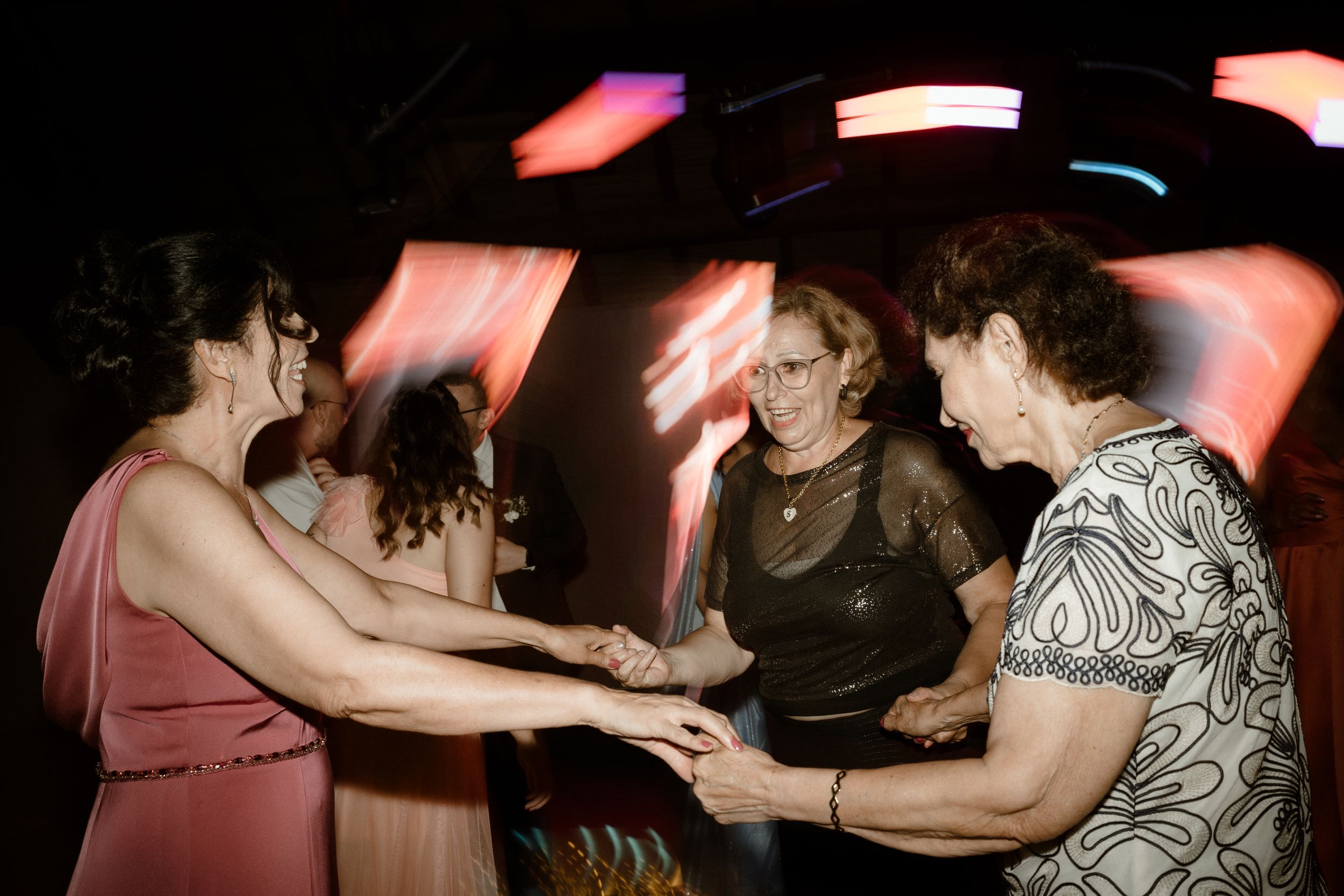 Party guests dancing together under vibrant red lighting effects.