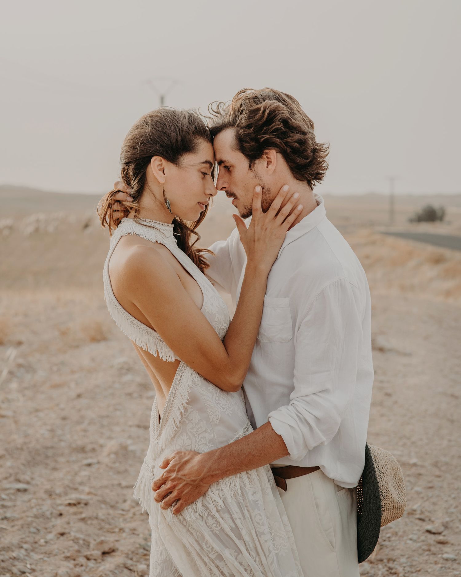 An intimate moment between a couple touching foreheads in a desert setting.