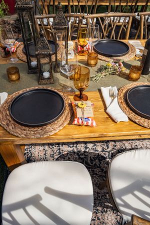 An elegant table setting with amber glassware, black plates and lantern centerpieces.
