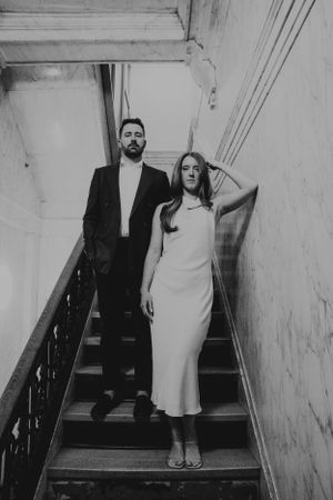 Artistic black and white photo of a couple on vintage stairs.