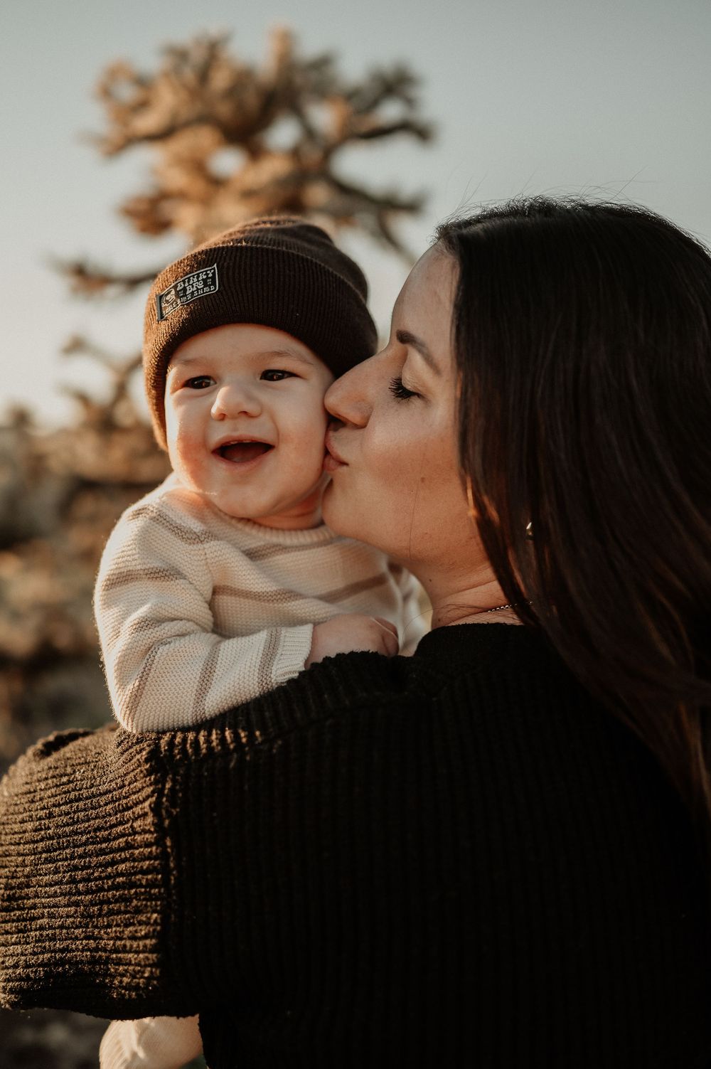 A mother and baby share tender moments in a series of warm sunset portraits showing affectionate kisses and smiles.