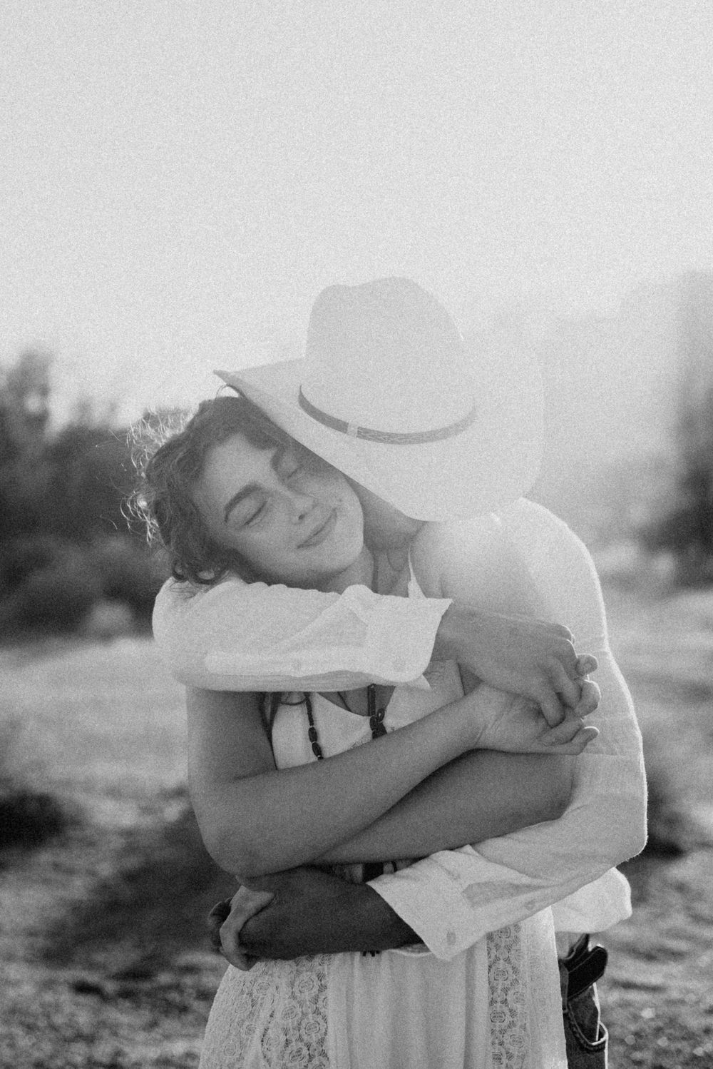 Black and white photo of two people embracing, one wearing a cowboy hat.