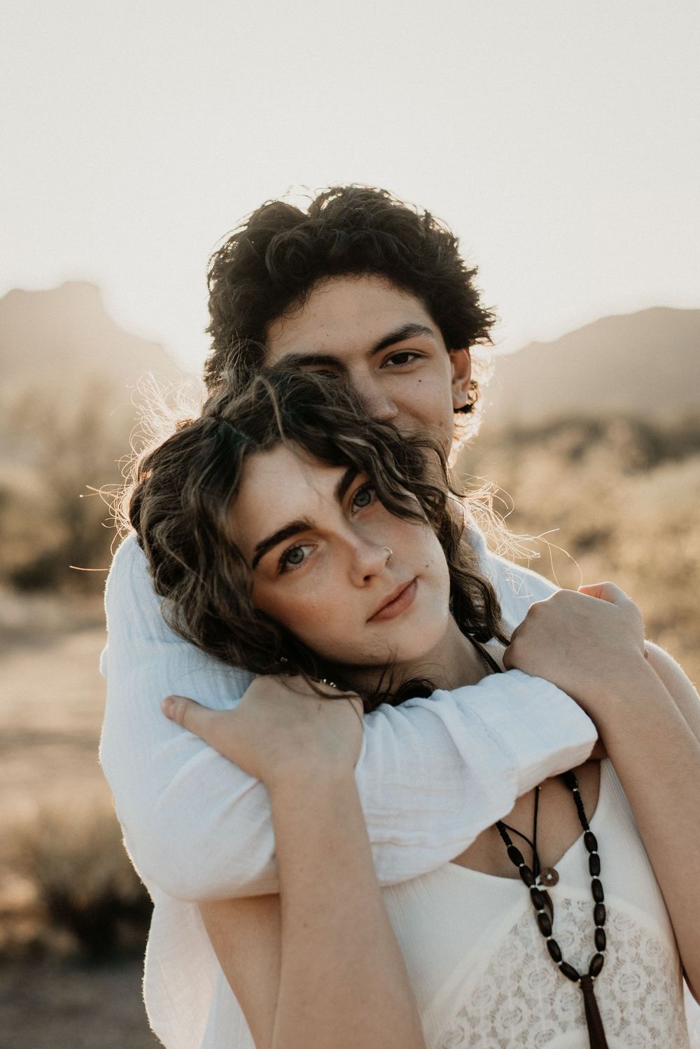 Intimate portrait of two people embracing in soft natural light.