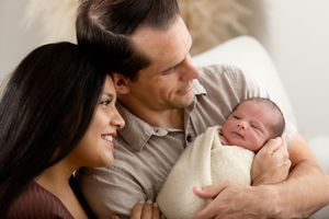 Lifestyle newborn photography session showing tender family moments on white sofa.