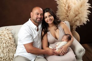 Intimate family photoshoot in white outfits against a warm brown backdrop.