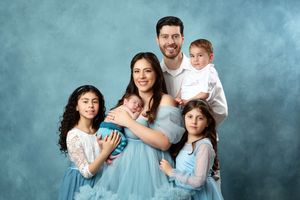 Family portrait session with coordinated blue outfits against ethereal backdrop.