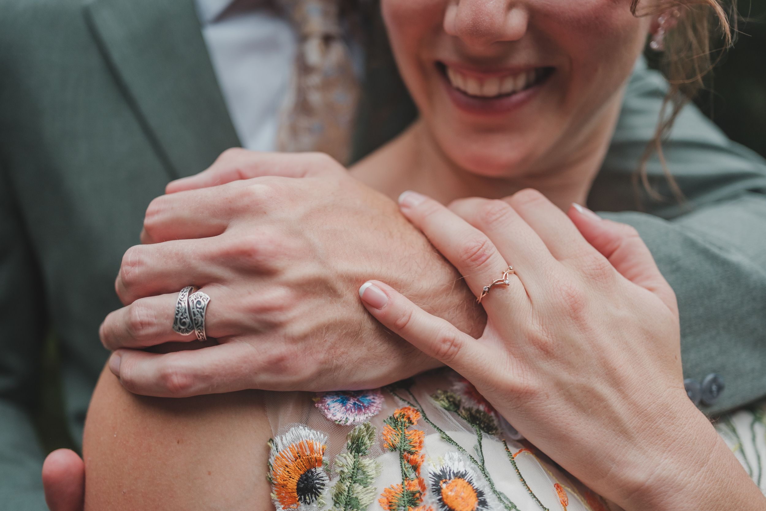 Close-up of hands showing off engagement rings against a floral patterned dress.
