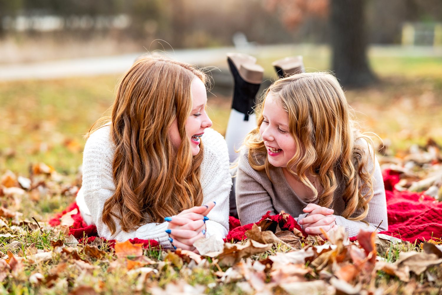 Two children sit together in tall grass during golden hour.