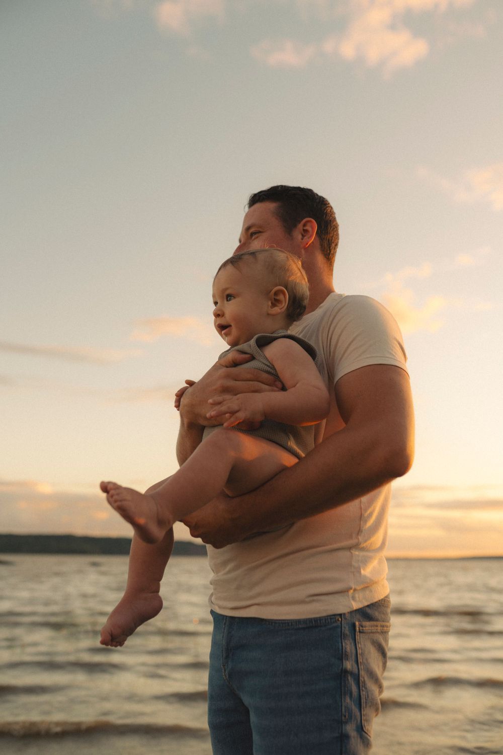A tender moment between parent and child against a sunset beach backdrop.