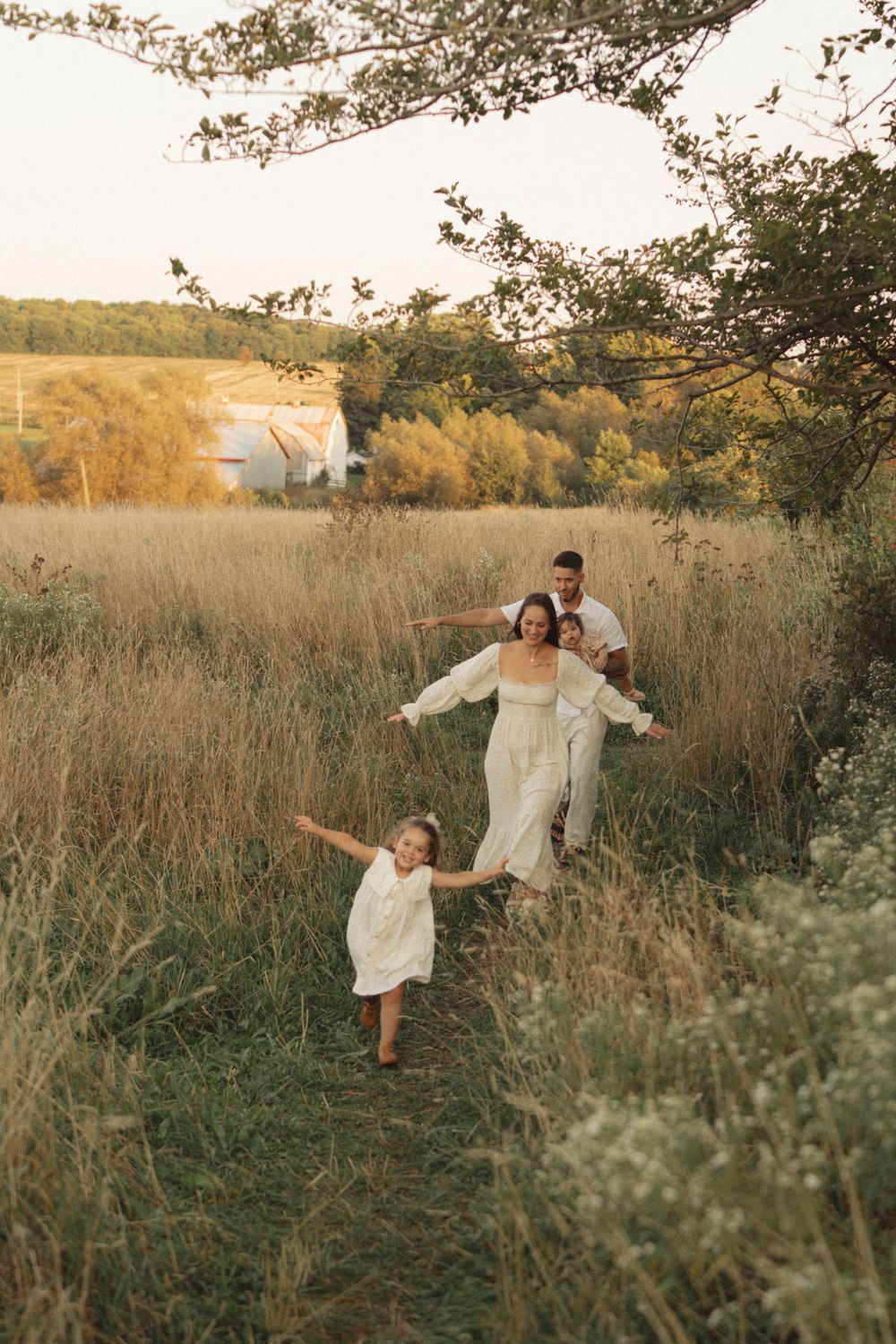 A family walks together down a grassy hill path during golden hour.