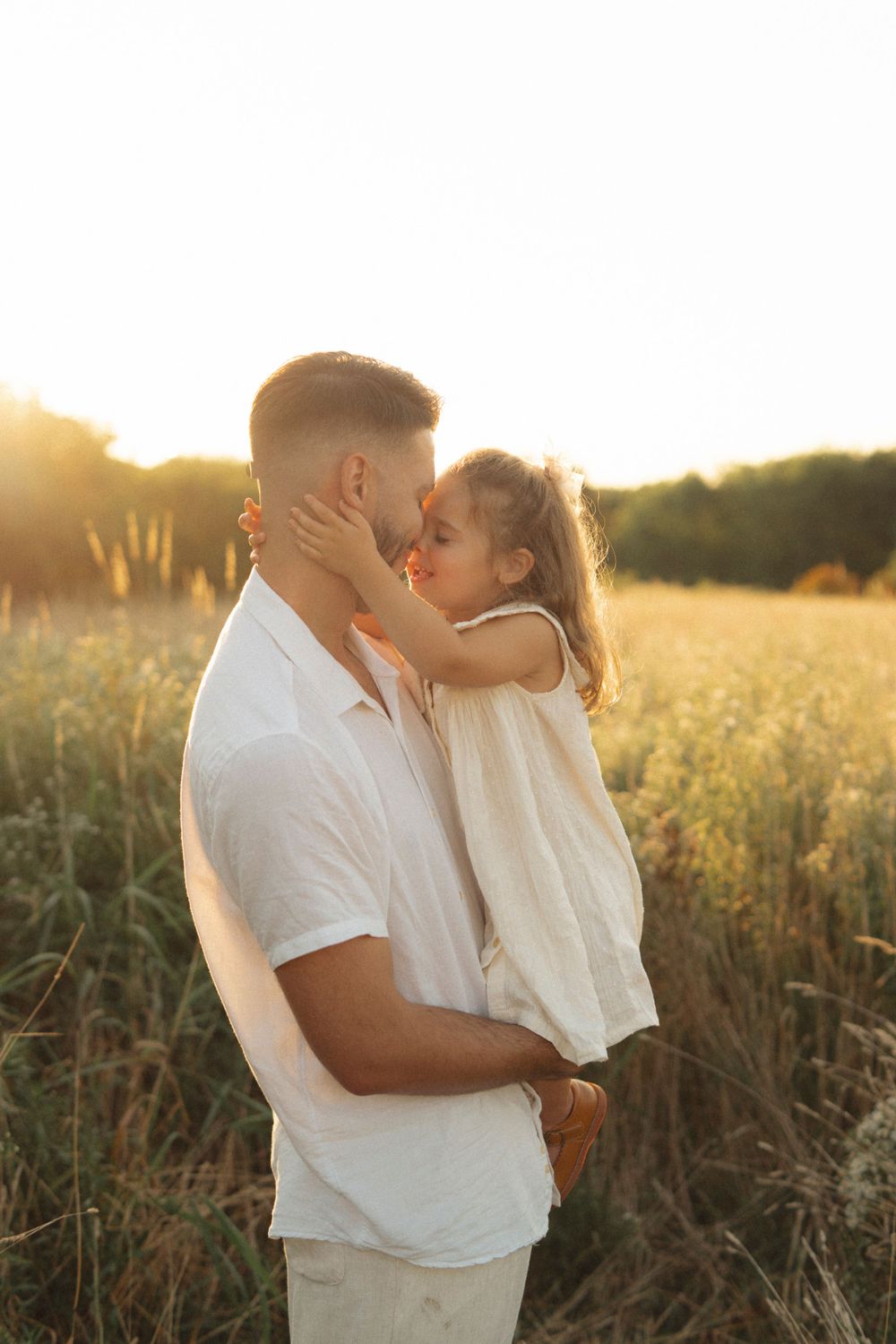 An intimate moment captured between parent and child in a sunlit field.