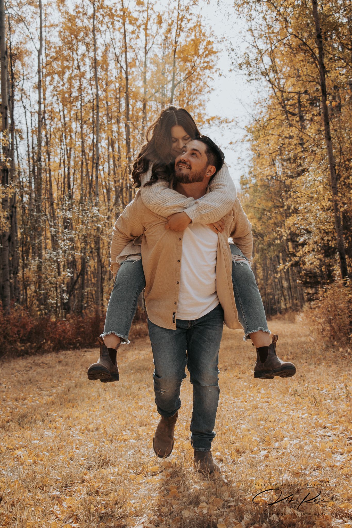 Playful engagement photo of a couple chasing each other around a barn in Fort St John