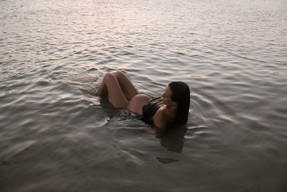 A person floats serenely in calm waters during sunset, creating a peaceful and dreamy atmosphere.