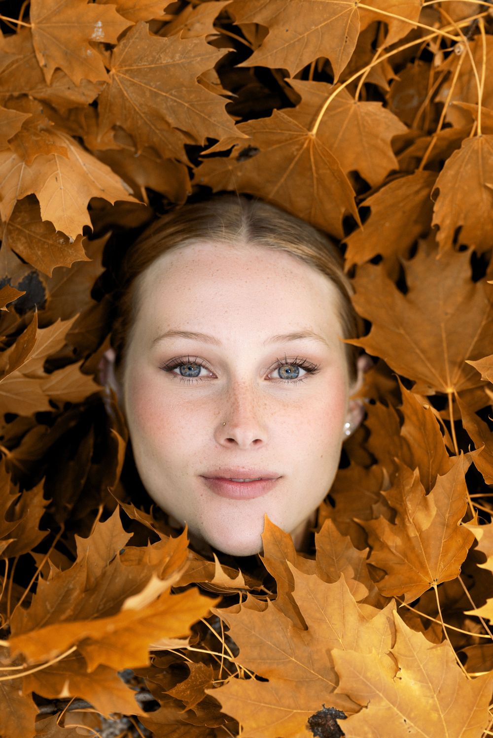 Creative portrait framed by golden autumn maple leaves.