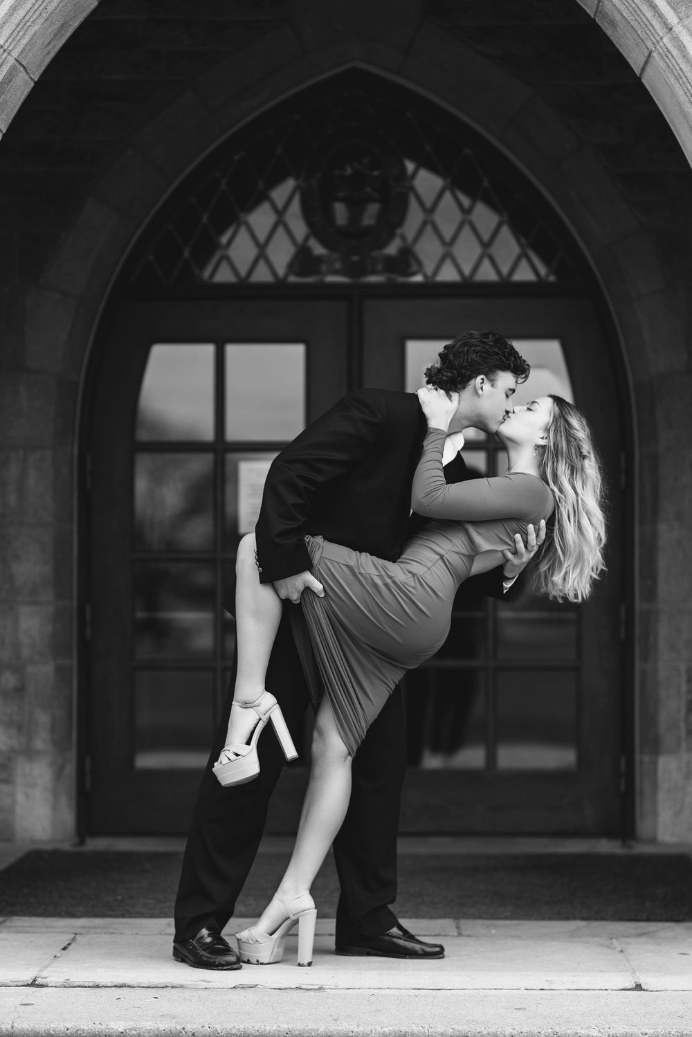 Romantic vintage-style dance dip pose in front of an arched doorway.