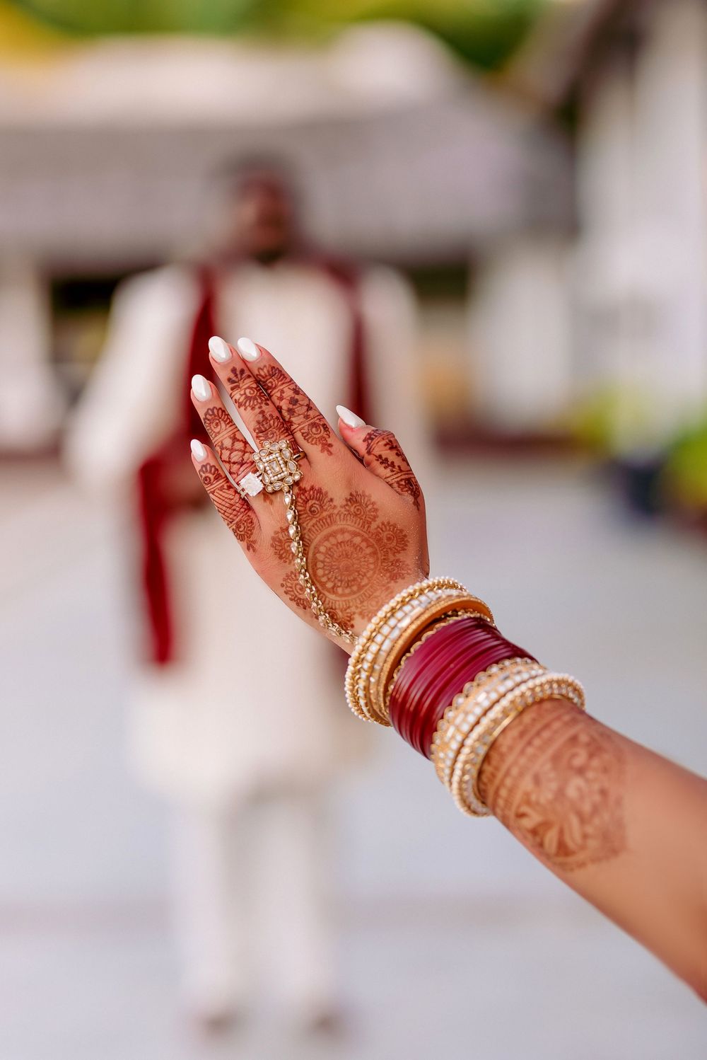 Hand adorned with intricate henna designs and traditional Indian wedding bangles and jewelry.