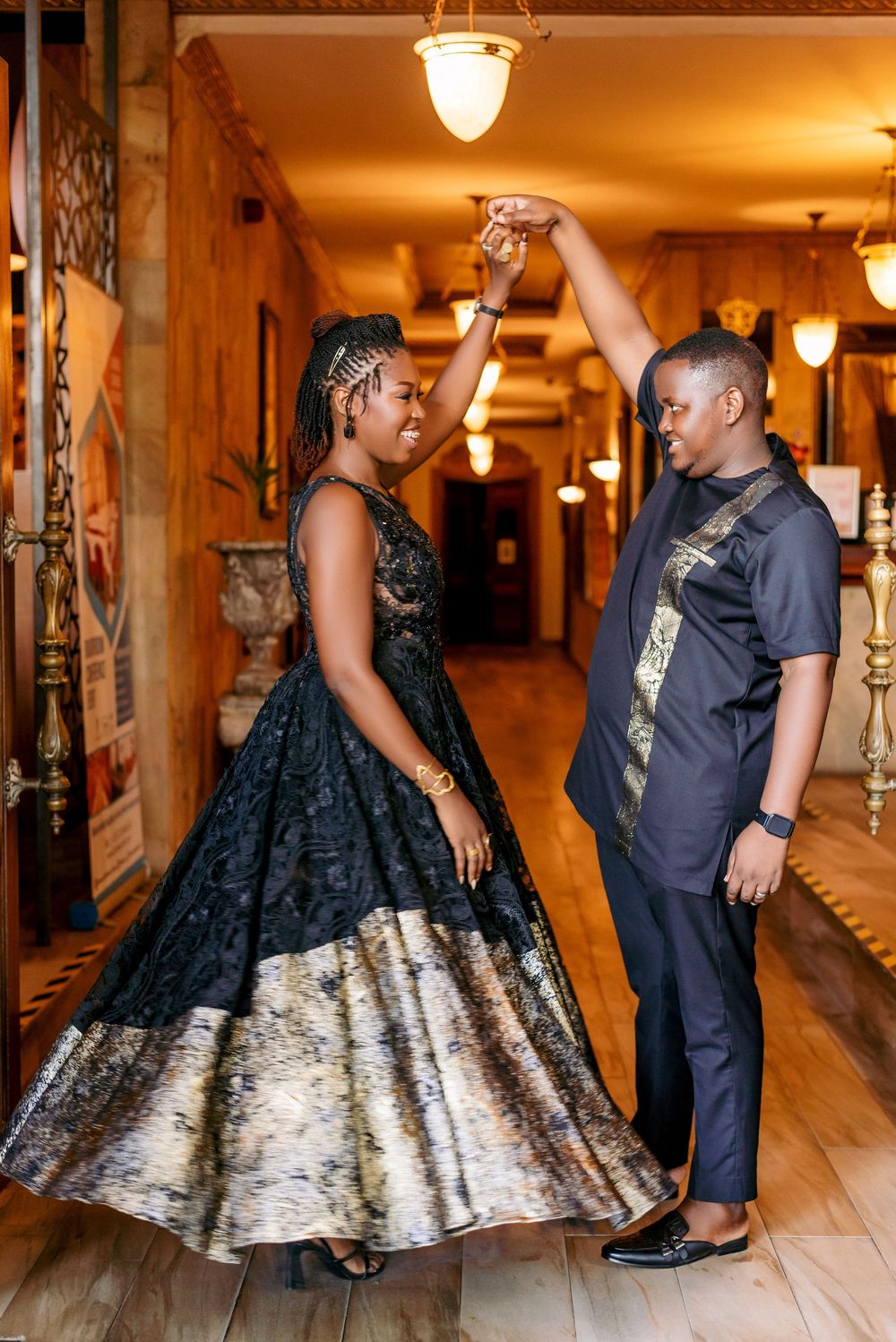 Couple in formal attire dances together in warmly lit hallway with vintage decor.