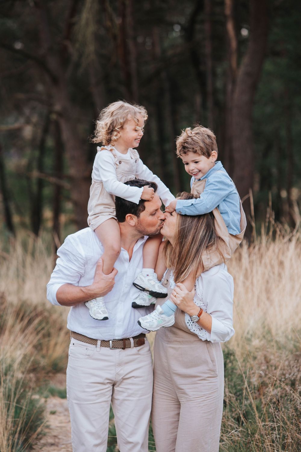 A family shares joyful moments together while walking through a scenic wooded trail at sunset.