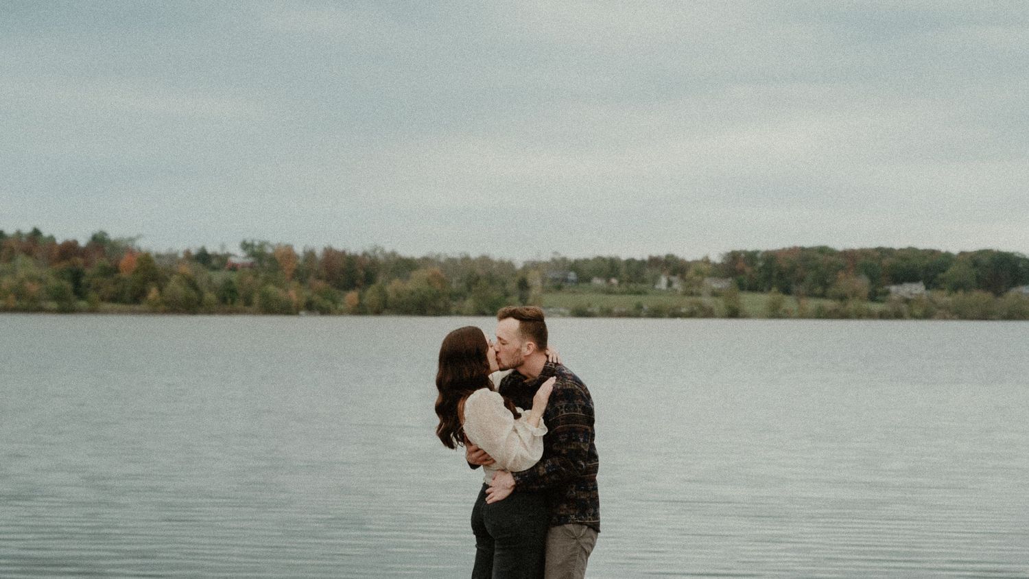 engaged couple kissing near lake. Peace valley Park, Lake Galena. vintage engagement photography. Grainy, blue lake. Romantic Bucks county