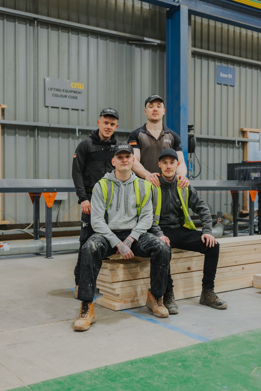 Workers in casual attire pose for group photo in industrial workspace.